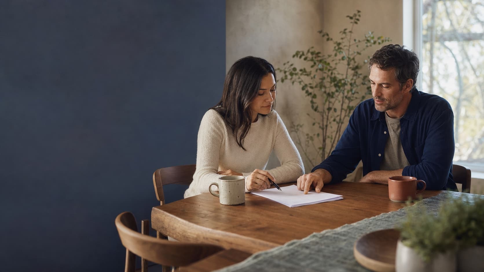 A couple calmly reviewing papers together at their dining table